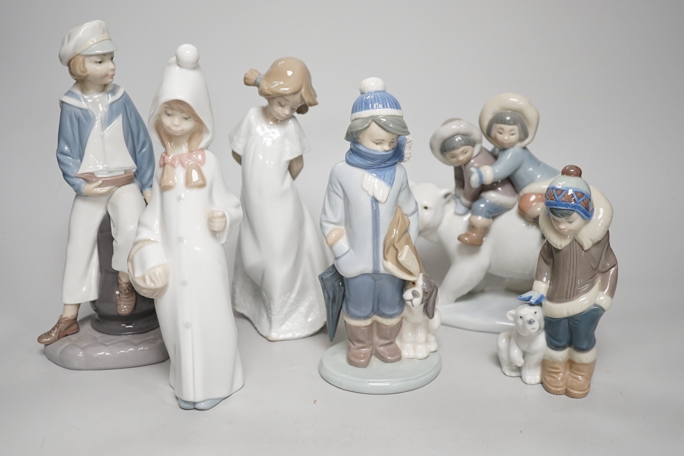 Seven Lladro figures; mother baby and child, boy with train, boy with sailing boat, Eskimo children on a polar bear and four others including a Nao example, the largest 28cm wide